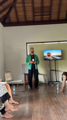 Man addresses seated group in bright Ubud room
