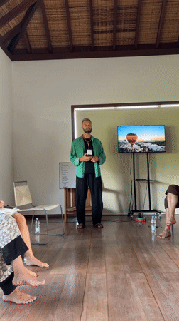 Man addresses seated group in bright Ubud room