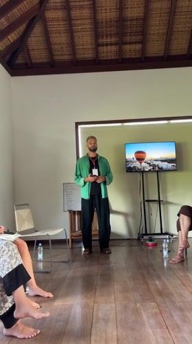 Man addresses seated group in bright Ubud room