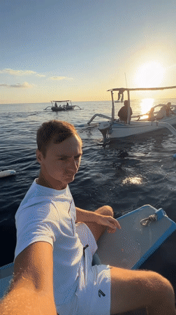 Dolphins surface beside a small boat off the Indonesian coast