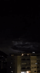 Lightning Storm Illuminates Buildings and Mountains at Night