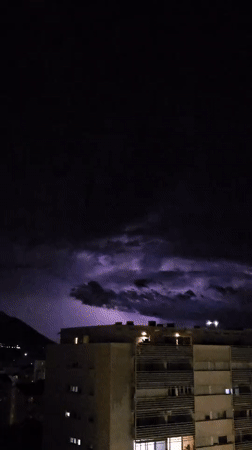 Lightning Storm Illuminates Buildings and Mountains at Night