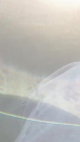 The video shows a police car with blue flashing lights. The car is labeled "POLITIA MILITARA". The camera is inside another vehicle, looking out at the police car. There is a white van in the background. The sky is blue and there are trees in the distance. The video is shaky and there is a lot of glare.