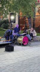 Street drummer performs in urban plaza during sunset