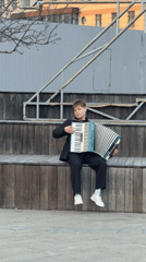 Street musician plays accordion on bench in Krasnoyarsk