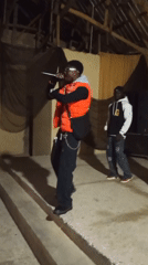 Rapper performs in black outfit and orange vest