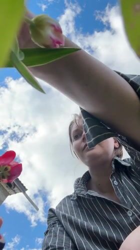 Woman gathers tulip bouquet under blue skies in Aksay, Kazakhstan
