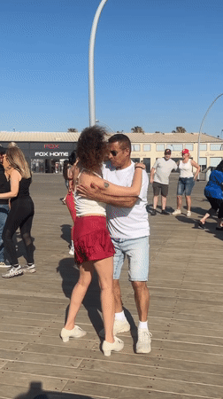 Group dances on Tel Aviv boardwalk near iconic city sign