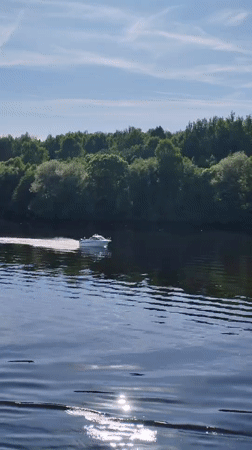 Motorboat crosses sunlit water near Novye Shatrishchi, Russia