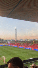 Football match underway in Barcelos stadium with red-clad supporters