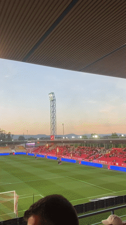 Football match underway in Barcelos stadium with red-clad supporters