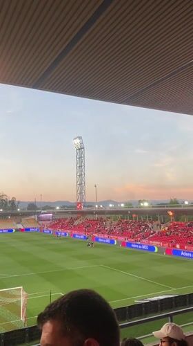 Football match underway in Barcelos stadium with red-clad supporters