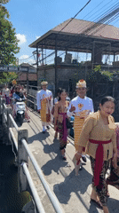 Traditional Balinese ceremony procession crosses bridge in Denpasar