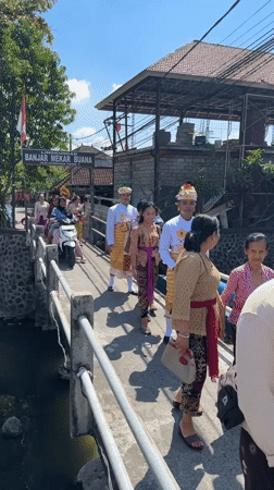 Traditional Balinese ceremony procession crosses bridge in Denpasar