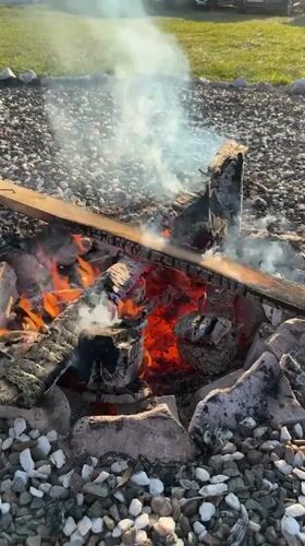 Campfire burns in stone ring in Vechernitsy, Russia