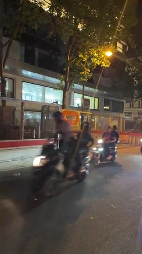 Two motorcycles pass through nighttime Paris street near construction