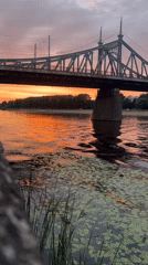 Metal bridge over still water at golden hour