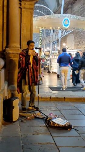 Street musician plays pan flute in historic Cuzco center