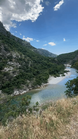 Tourists cross rusty suspension bridge over turquoise Montenegro river