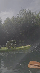 Kayaker enjoys sunny afternoon paddle on tree-lined waterway
