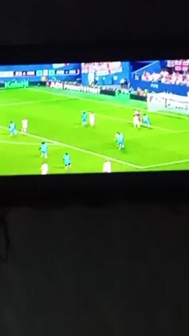 The video shows a television screen displaying a soccer match. The game appears to be a professional match given the stadium lighting and the presence of a scoreboard. The field is green, and players are visible in blue and white uniforms.

The video cuts between different shots of the game. One shot shows a player in a blue jersey with his back to the camera. Another shot focuses on a player with blonde hair, looking intently at the game. A third shot shows a coach or manager in a green shirt gesturing with his hands, likely directing his players.

The scoreboard at the top of the screen provides some context. While the exact team names are not fully legible, the score is displayed as 0-0. There are also indicators for time, showing "0:00" and "0:00", suggesting the beginning of a match or half. The presence of "VISA" branding on a blue backdrop indicates a sponsor.

The overall atmosphere appears to be that of a competitive sporting event. The lighting suggests it is likely an evening match or an indoor stadium. No specific weather conditions are discernible. The location is stated to be Olișcani, Moldova, implying this is where the broadcast is being viewed or potentially where the match is taking place, although the stadium itself does not offer specific geographical cues. The emotions of the players and coaches are difficult to gauge due to the image quality and distance, but the focused expressions suggest engagement with the game.