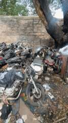 Vehicle scrapyard documented in Bengaluru with damaged motorcycles, rickshaw