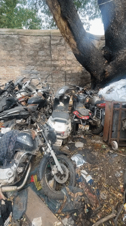 Vehicle scrapyard documented in Bengaluru with damaged motorcycles, rickshaw
