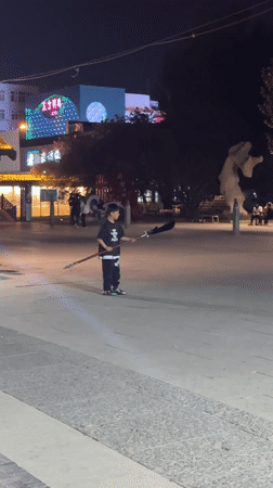 Boy practices martial arts near traditional gate in Jinzhou