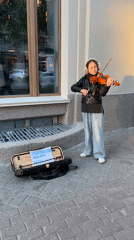 Young violinist performs on Novosibirsk sidewalk during afternoon