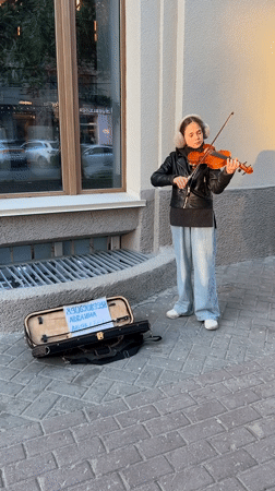 Young violinist performs on Novosibirsk sidewalk during afternoon