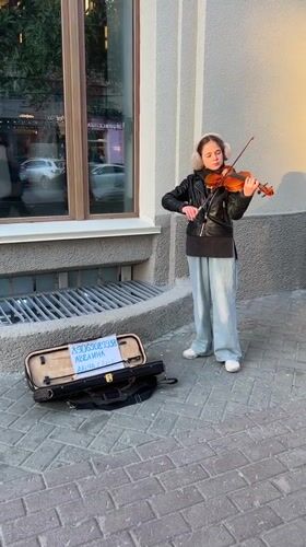 Young violinist performs on Novosibirsk sidewalk during afternoon