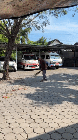 Man sweeps paved area in sunny Kebonsari morning