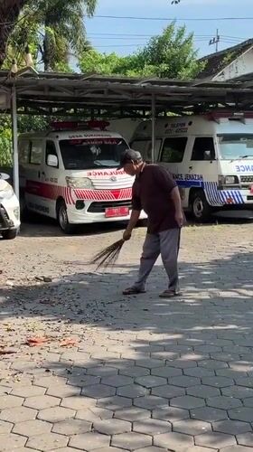 Man sweeps paved area in sunny Kebonsari morning
