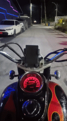 Motorcyclist rides through illuminated Baan Chaweng streets at night