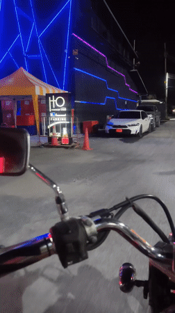 Motorcyclist rides through illuminated Baan Chaweng streets at night