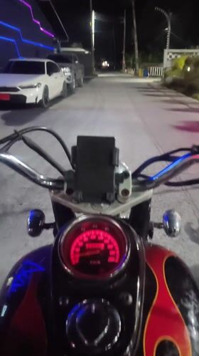Motorcyclist rides through illuminated Baan Chaweng streets at night