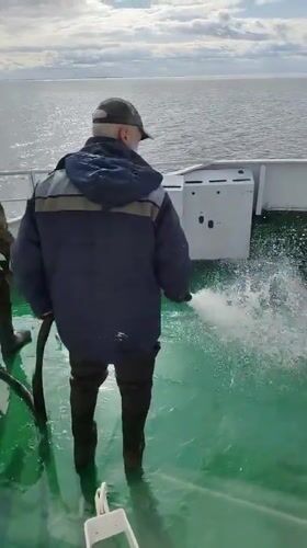 Crew member performs deck maintenance aboard vessel in Russian waters