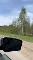 Vehicle mirror captures rural road scene in Russia