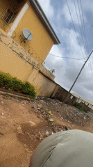 Motorcyclist travels dirt road amid litter in Nigeria