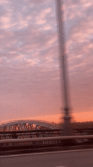 Pink sunset captured from moving vehicle over Moscow bridge