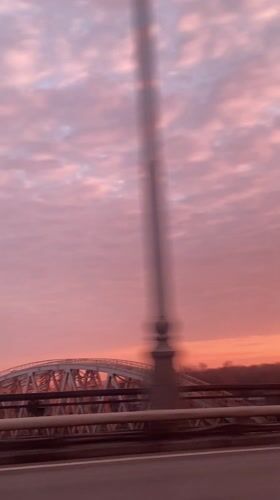 Pink sunset captured from moving vehicle over Moscow bridge