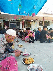Outdoor communal meal under a blue tarp in Galis, Indonesia