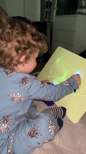 Child plays with glowing drawing board in Klin bedroom