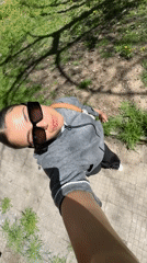 Woman films outdoor selfie video near building and grass
