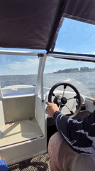 Boat moving through Astrakhan waterways past barges and nets