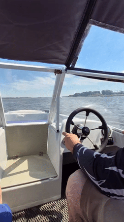 Boat moving through Astrakhan waterways past barges and nets
