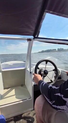 Boat moving through Astrakhan waterways past barges and nets