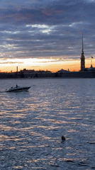Speedboat crosses Saint Petersburg river at sunset, witnessed from embankment