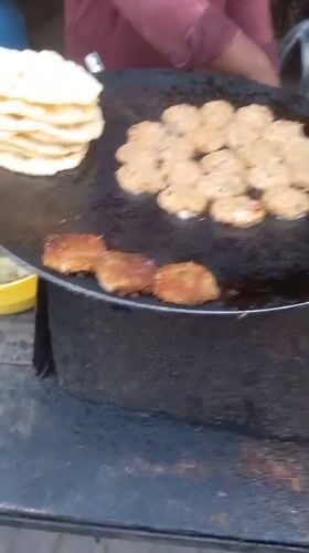Street vendor prepares food on griddle in Kalpi