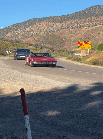 Vintage car convoy travels mountain roads in Morocco